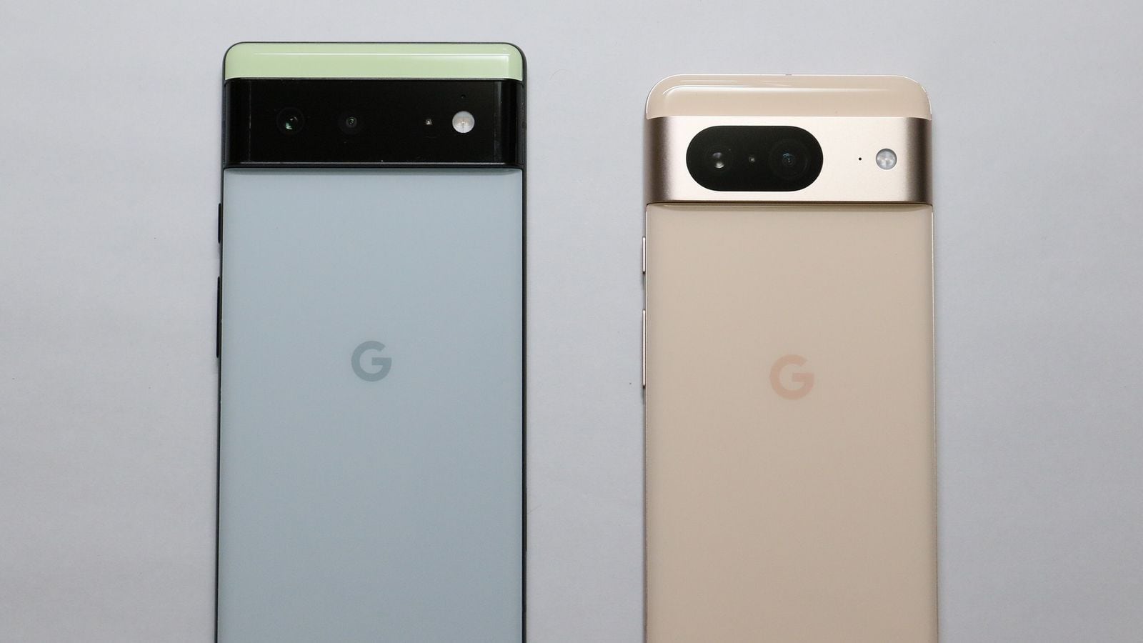 Dva telefony Google Pixel vedle sebe zezadu, zelený Pixel 6 Pro a zlatý Pixel 8