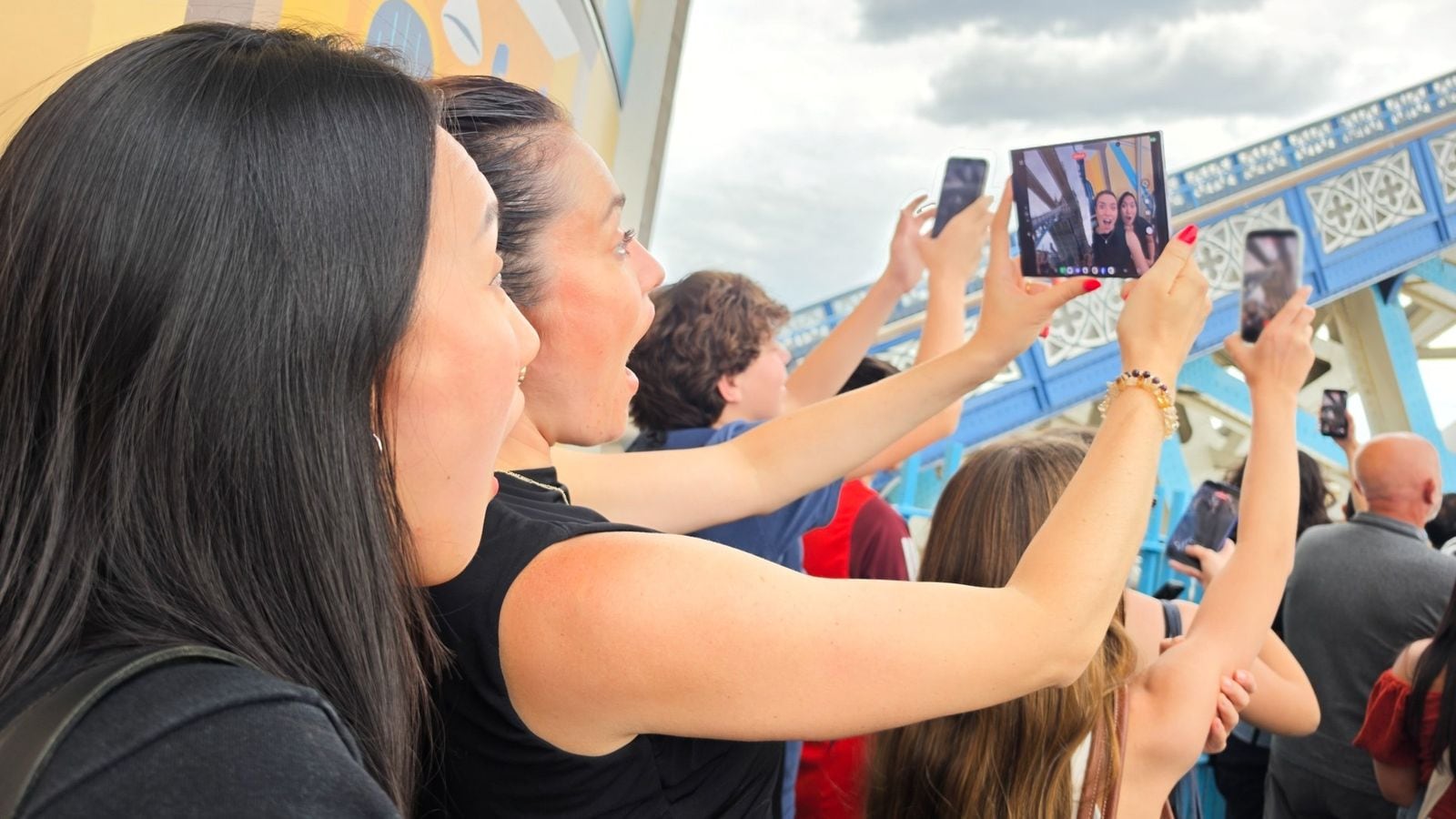Žena drží rozložený Samsung Galaxy Z Fold a fotografuje v davu na Tower Bridge