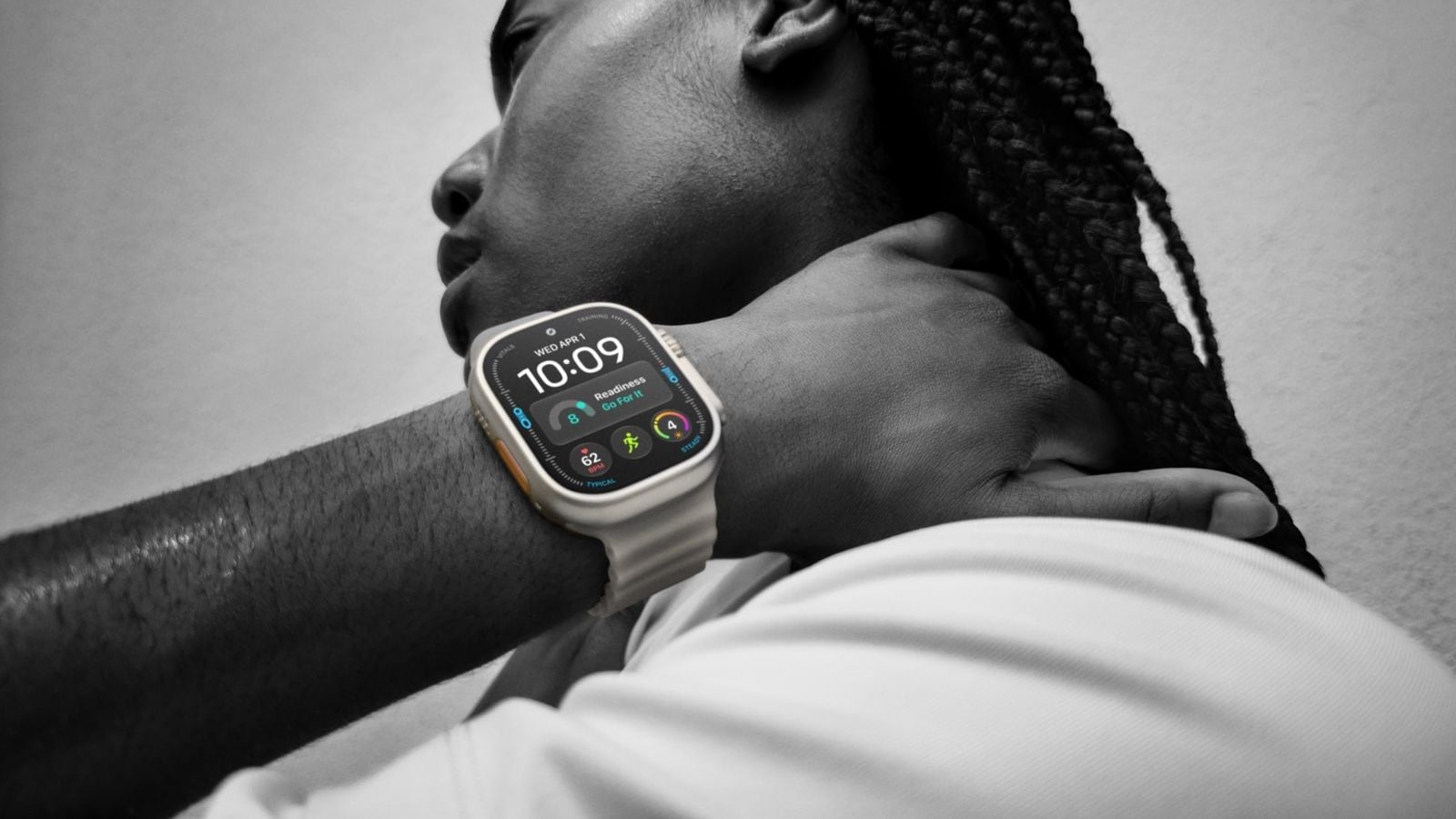 Černobílá fotografie uživatele s Apple Watch Ultra 4, na obrazovce je zobrazeno doporučení Go For It